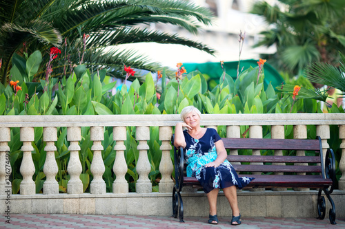 An elderly woman at the tropical resort, palm trees at the background photo