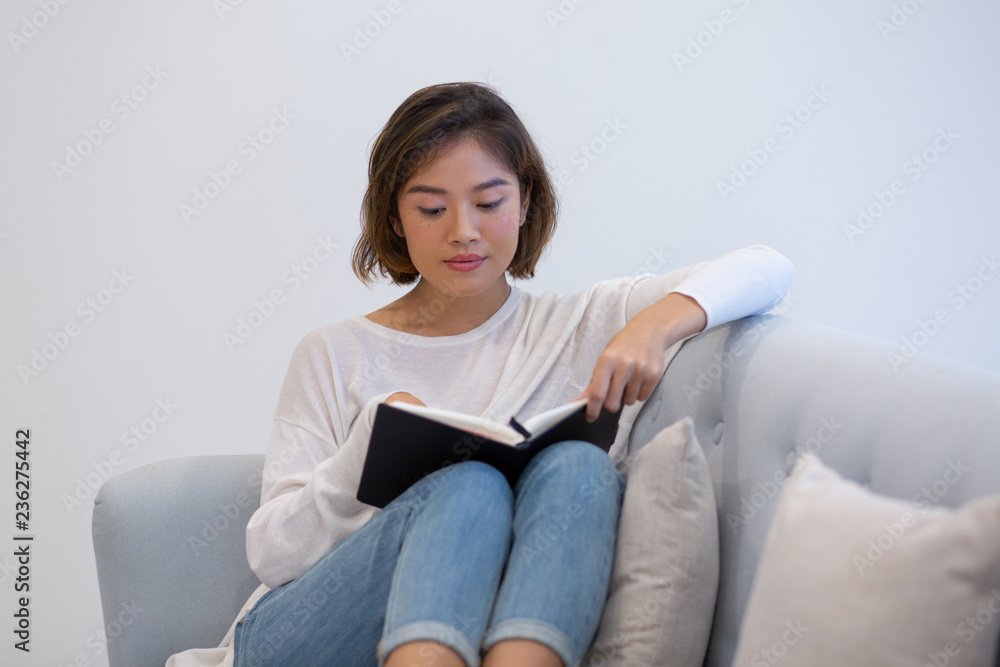 Serious Asian student preparing for test. Beautiful young girl reading her study notes at home. Self-tuition concept Serious Asian student preparing for test. Beautiful young girl reading her study notes at home. Self-tuition concept