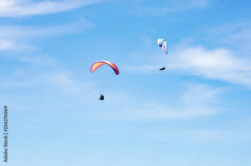 Two paragliders against the sky. Russia, Republic of Crimea. 06.13.2018. Flight of two paragliders on the background of the sky with light clouds Two paragliders against the sky. Russia, Republic of Crimea. 06.13.2018. Flight of two paragliders on the background of the sky with light clouds