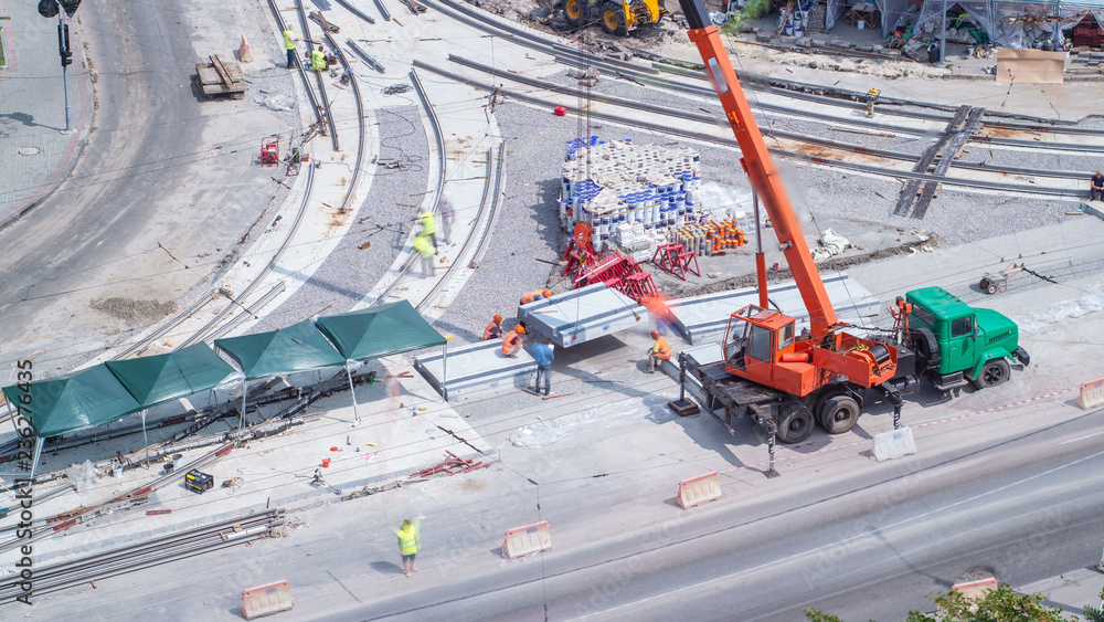 Unloading concrete plates from truck by crane at road construction site timelapse.