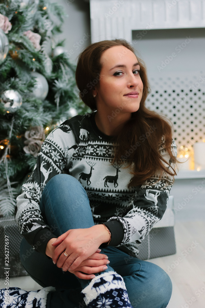 Beautiful girl or young woman sitting near the christmas tree. Beautiful girl or young woman sitting near the christmas tree.