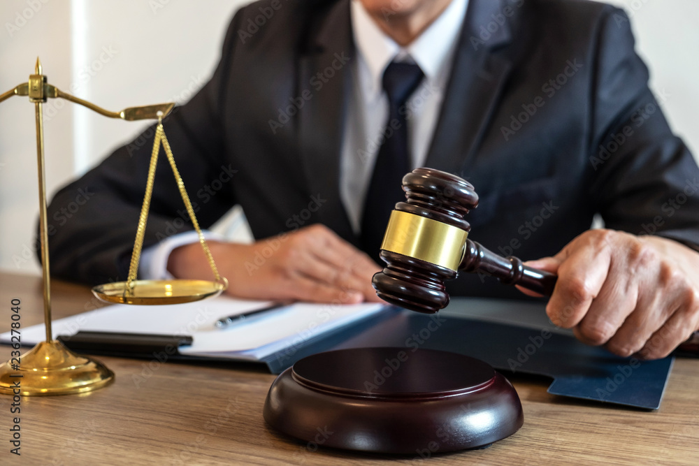 Legal law, advice and justice concept, counselor lawyer or notary working on a documents and report of the important case and wooden gavel, brass scale on table in courtroom Legal law, advice and justice concept, counselor lawyer or notary working on a documents and report of the important case and wooden gavel, brass scale on table in courtroom