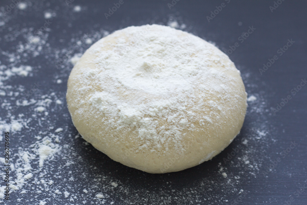 fresh raw baking dough sprinkled with flour on a dark background fresh raw baking dough sprinkled with flour on a dark background