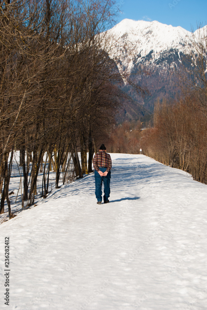 One elderly with wool hat walking on a snowy road