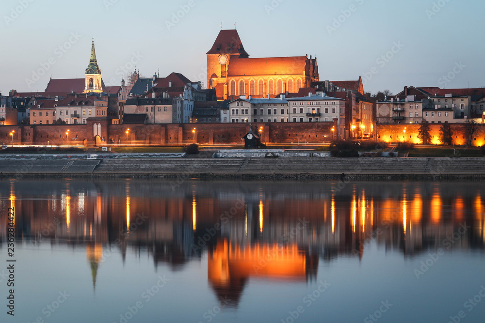 TORUN, POLAND - Gothic Torun Cathedral and the panorama of the Old Town district in Torun with beautiful illuminations and evening sky water reflections