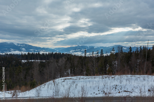 Evening winter mountain ridge and sun rays from cloudy sky photo