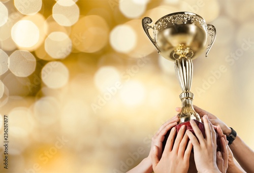 Hands holding golden trophy on background