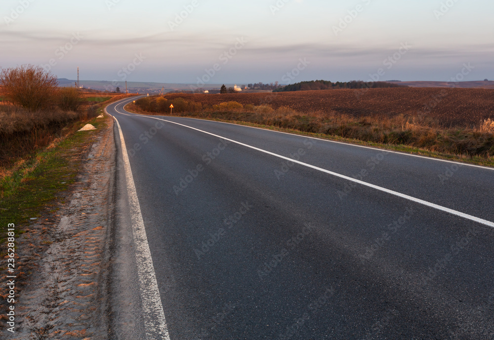 Fototapeta premium Road through the spring morning fields and countryside.