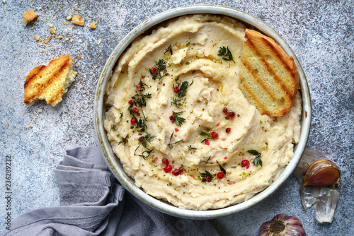 White bean hummus with baked garlic and dried herbs.Top view with copy space.
