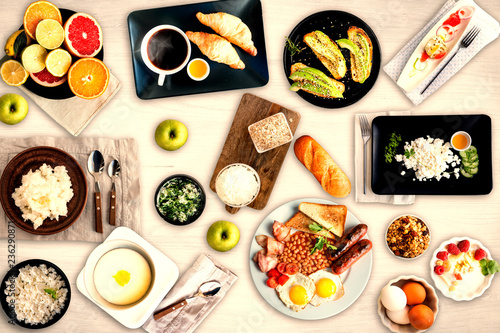 Set of different breakfasts on white wooden table. Fruits, croissants, apples, honey, coffee, curd, cheese, porridge, bread, english breakfast, avocado, semolina, eggs, sandwiches.. Top view.
