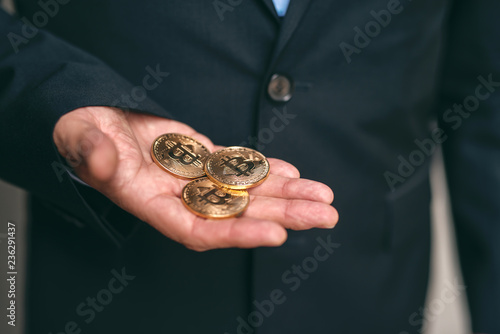 Close up of senior adult businessman holding bit-coins in hand.