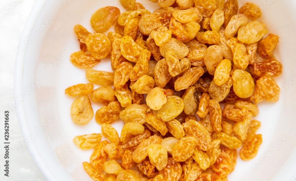 Yellow raisins in a plate as background Yellow raisins in a plate as background