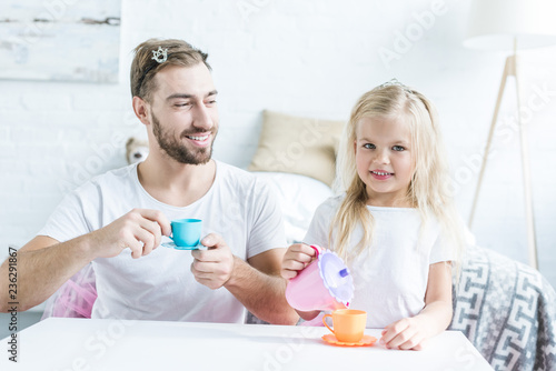 happy father and daughter playing together and pretending to have tea party