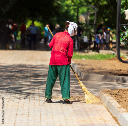 Woman sweeping on the pavement in the park