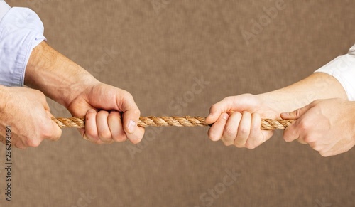 Tug war, two businessmen pulling a rope in opposite directions