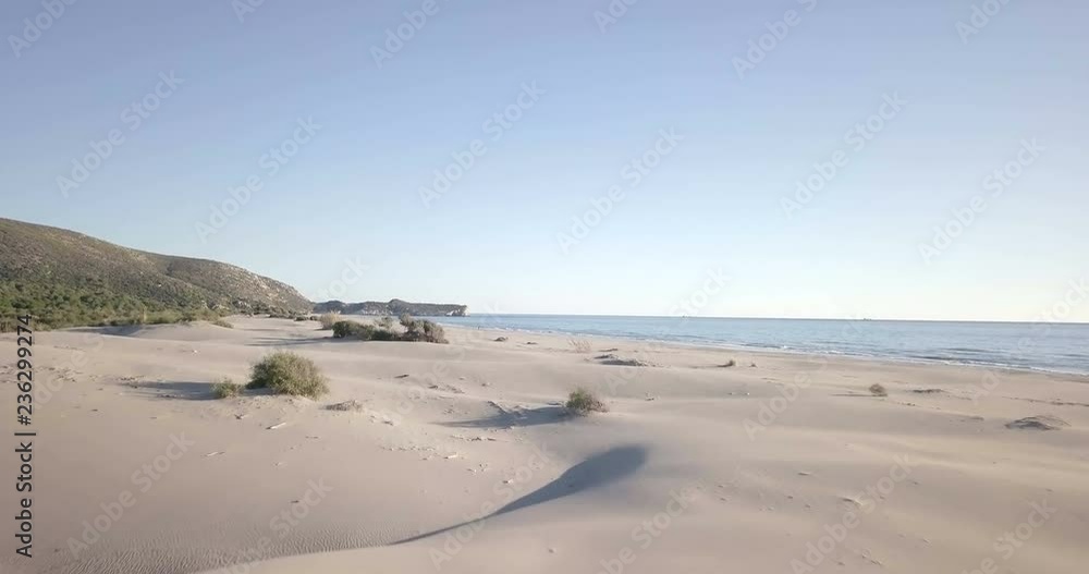 Low altitude forward aerial drone video over sand dunes of empty beach ascending to reveal ocean in Patara, Turkey. 4k at 23.97fps