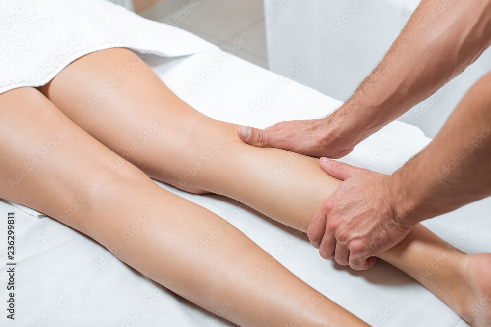 cropped view of man massaging woman legs in spa center