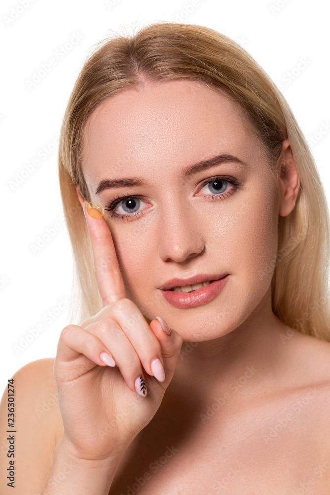 Young woman holding contact lens on index finger with copy space. Close up face of healthy beautiful woman about to wear contact lens.