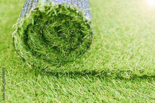 Artificial turf roll. Synthetic grass lawn laying background.