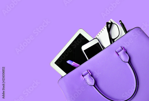Business woman's everyday-life travel accessories flat lay on light purple background with formal light purple handbag, a cellphone, blank notepad, luxury pen, glasses and lipstick, copy space