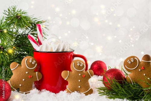 Cozy winter composition with a red cup of hot chocolate with marshmallows gingerbread man cookies  on a light festive background.