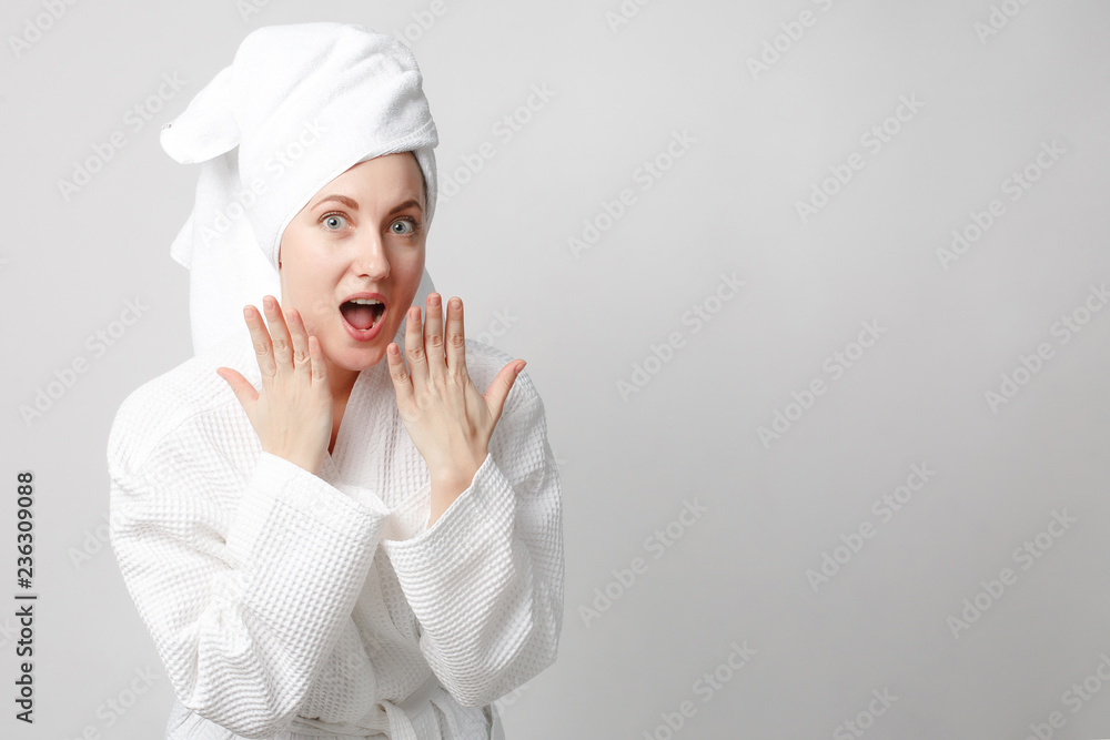 Beautiful girl wearing white bathrobe with towel on the head, looking at camera and smiling, a model with light nude make-up, white studio background, beauty photo, copy space. Beautiful girl wearing white bathrobe with towel on the head, looking at camera and smiling, a model with light nude make-up, white studio background, beauty photo, copy space.