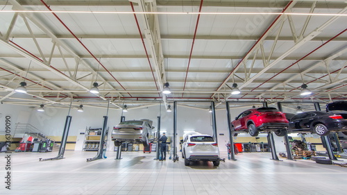 Fotografie, Tablou Cars moves on lifts in modern service station and men repair cars timelapse