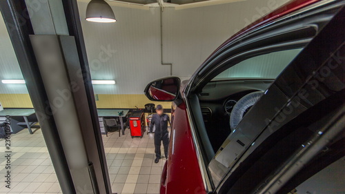 car mechanic drive red car from lift to wheels alignment camber check at repair service station timelapse