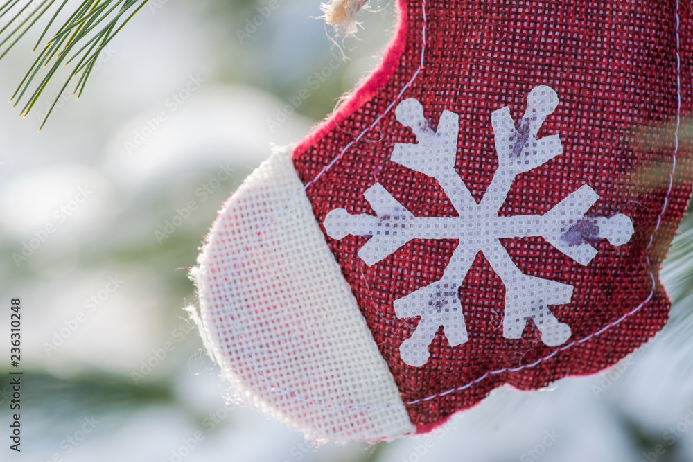 Φωτογραφία Winter holiday decoration concept: snowflake crochet Christmas stocking and frozen snow covered pine tree twigs in forest preserve park