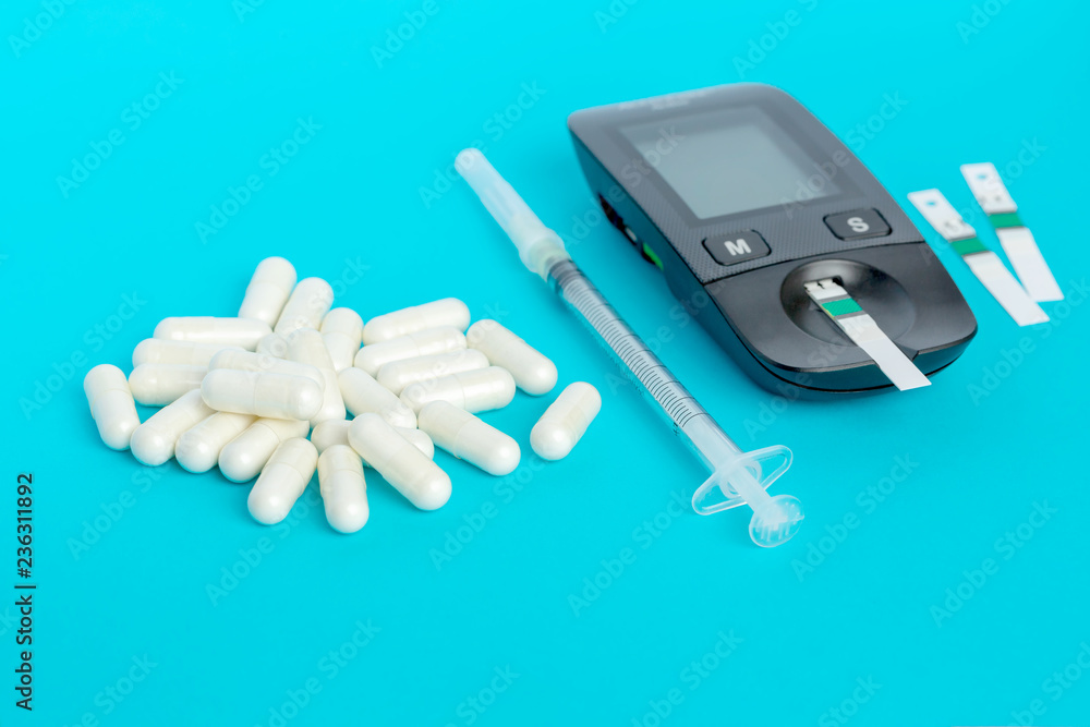 Glucometer, medication, syringe lie on a blue background Glucometer, medication, syringe lie on a blue background