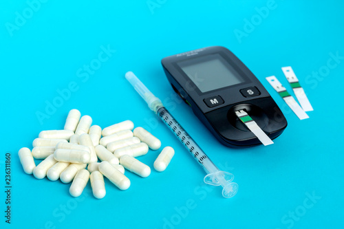 Glucometer, medication, syringe lie on a blue background photo