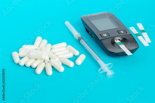 Glucometer, medication, syringe lie on a blue background photo