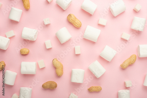 White marshmallows, with pieces of sugar, and nuts on a pink background. The ability to use as a background, the concept of the concept of winter food. Flyte lay or on top.