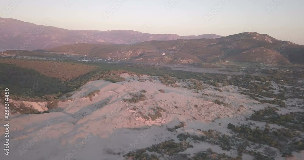 High altitude aerial drone video orbiting left around tall sand dune mountains towards Lycian ruins at sunset in Patara, Turkey. 4k at 23.97fps High altitude aerial drone video orbiting left around tall sand dune mountains towards Lycian ruins at sunset in Patara, Turkey. 4k at 23.97fps