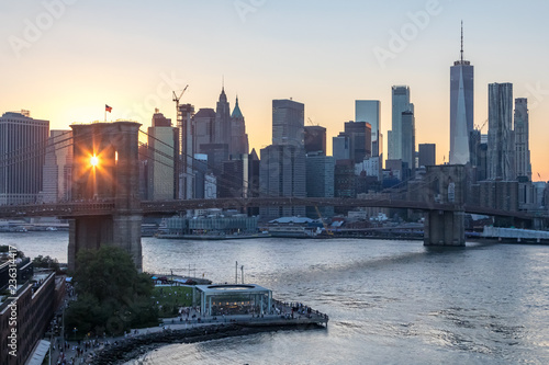 New York City - Rays of sunlight shine through the arches of the Brooklyn Bridge with the downtown Manhattan skyline in the background