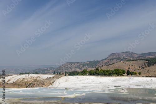 cotton castle in Pamukkale, Turkey. White limestone cliffs with water, against the sky