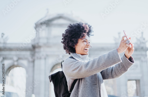 Portrait of attractive afro woman using mobile phone in Madrid, Spain. Puerta de Alcala.