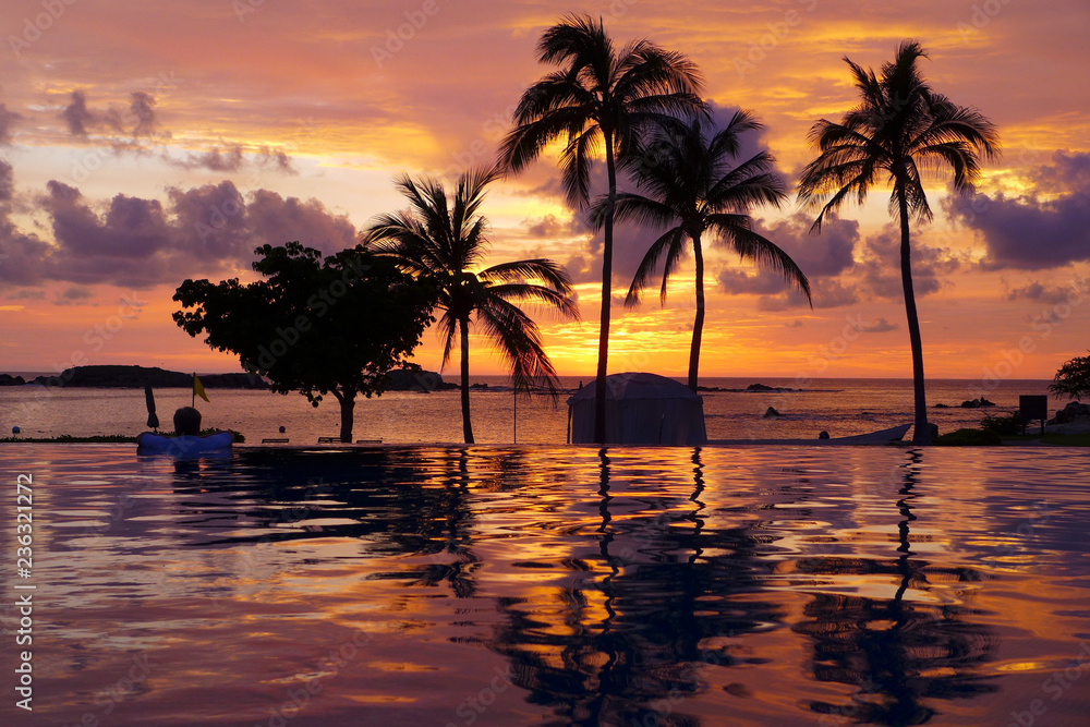 Tropical paradise sunset reflecting on a swimming pool and sandy beach in Punta Mita, Mexico