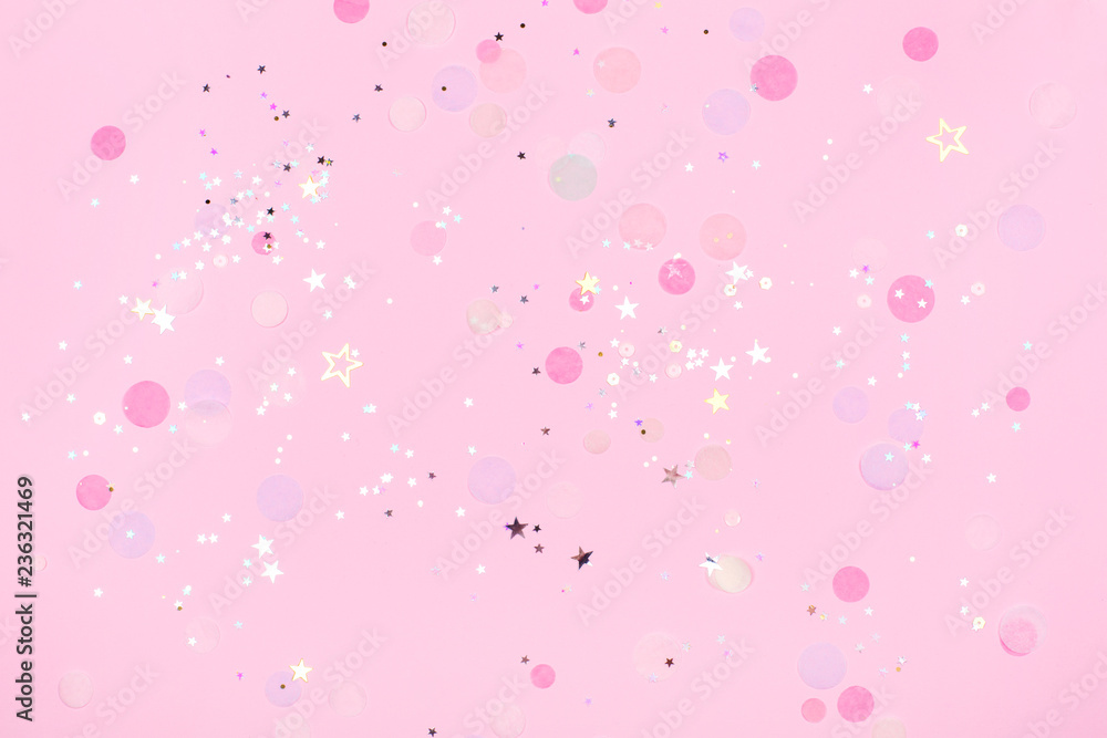 Pink pastel festive background with confetti and sparkles. Flat lay style.