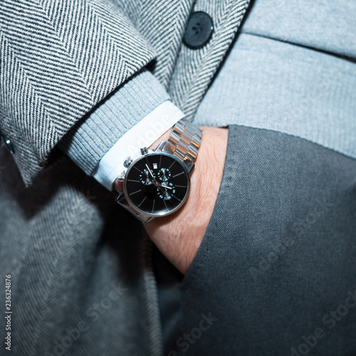 Vintage smart casual outfit outdoor in jacket. Fashion model man posing in grey italian suit.Suited man posing.closeup fashion image luxury watch on wrist of man.body detail of a business man.