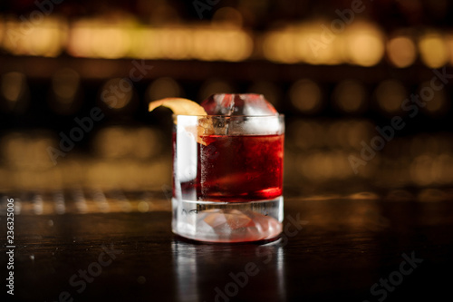 Elegant glass of tasty fresh and strong whiskey drink decorated with orange peel on bar counter