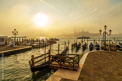 Gondolas in Venice at sunrise with Saint Giorgio island in morning fog, as seen from San Marco square