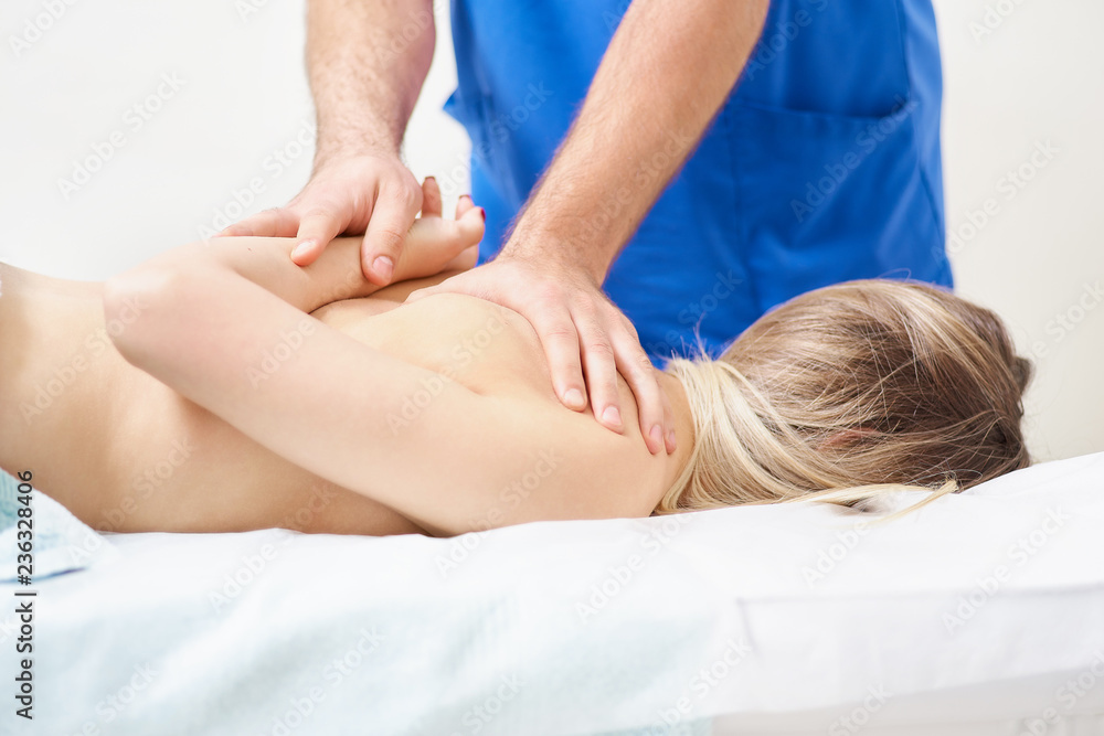 Physiotherapist doing healing treatment on man's back. Therapist wearing blue uniform. Osteopathy. Chiropractic adjustment, patient lying on massage table Physiotherapist doing healing treatment on man's back. Therapist wearing blue uniform. Osteopathy. Chiropractic adjustment, patient lying on massage table