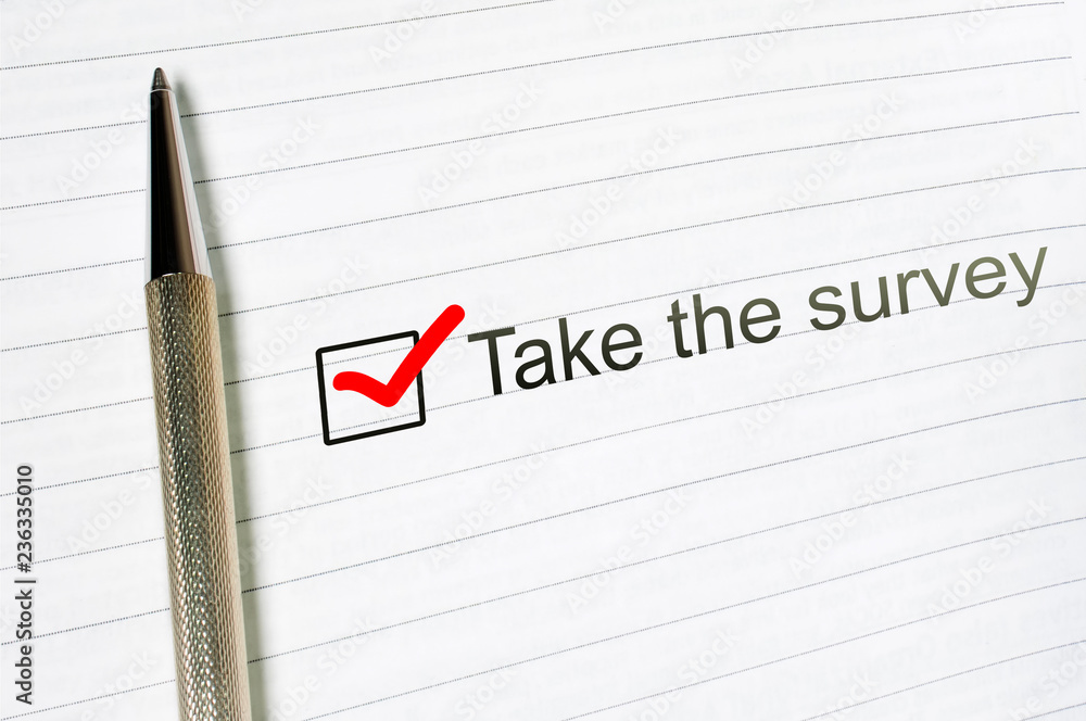 Take survey check box with a pen on lined paper background Take survey check box with a pen on lined paper background