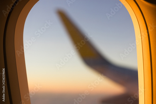 Sunlight on plane window with wing blurred on background. Air transportation concept