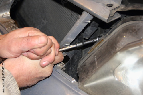 Men's rough hand unscrews the socket wrench with an extension cord car headlight - repair of vehicles, disassembling