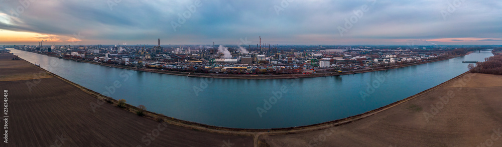 Obraz premium Industrial landscape with the river Rhine and chemical production plants at Ludwigshafen as seen from Mannheim in Germany.