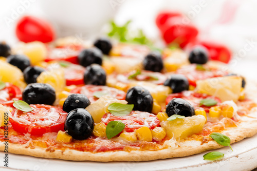 Pizza with tomatoes, mozzarella cheese, olives, corn and basil. Traditional italian cuisine