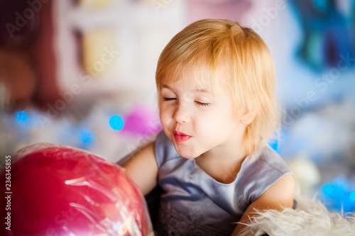 Portrait of little blonde smiling girl playing with toy candy. Christmas and New Year theme