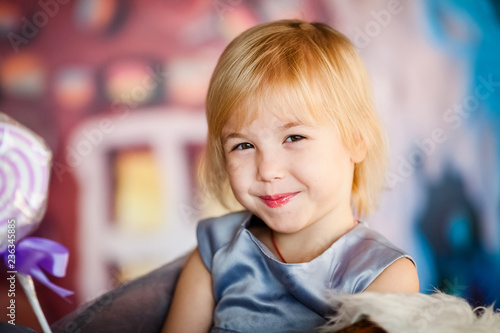Portrait of little blonde smiling girl playing with toy candy. Christmas and New Year theme